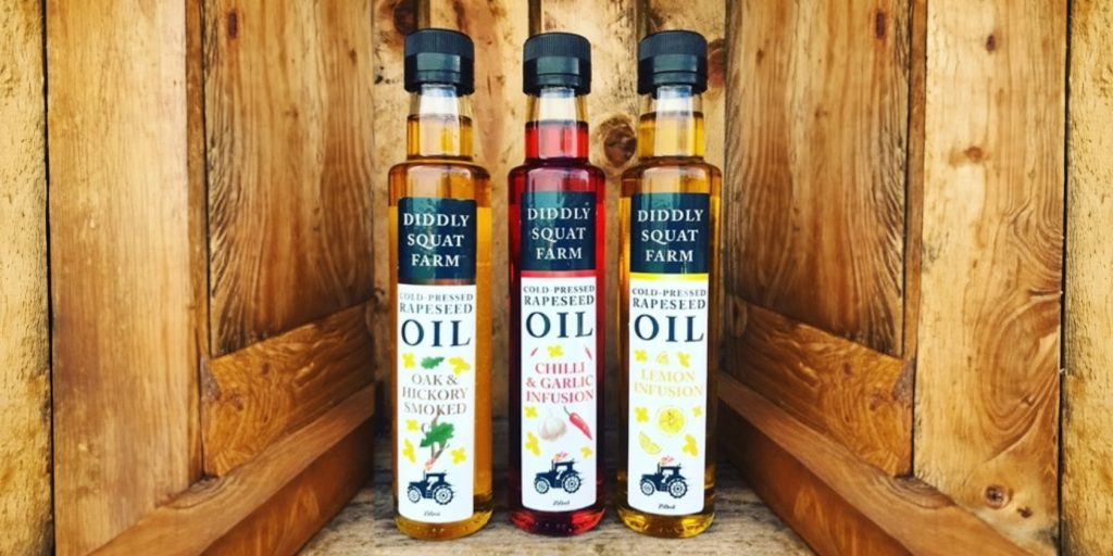 Three bottles of Diddly Squat rapeseed oil in a wooden barn